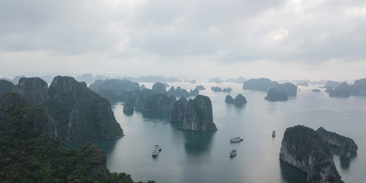 An array of small tropical islands with high cliffs and jungle on top. Boats sail between them.